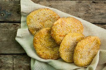A few round cheese cakes with sesame seeds on a wooden background.
