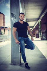 Handsome muscular blond man standing in city setting or former industrial environment