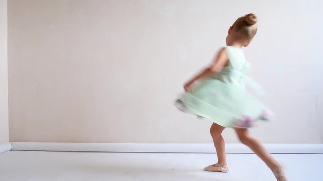 A cute girl is in her ballet uniform dancing