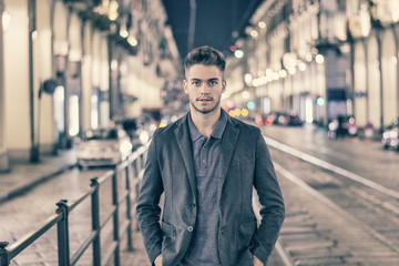 Obraz premium Attractive young man portrait at night with city lights behind him in Turin, Italy