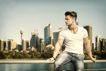 Fototapeta na wymiar Handsome man sitting on handrail on the background of city skyline. 