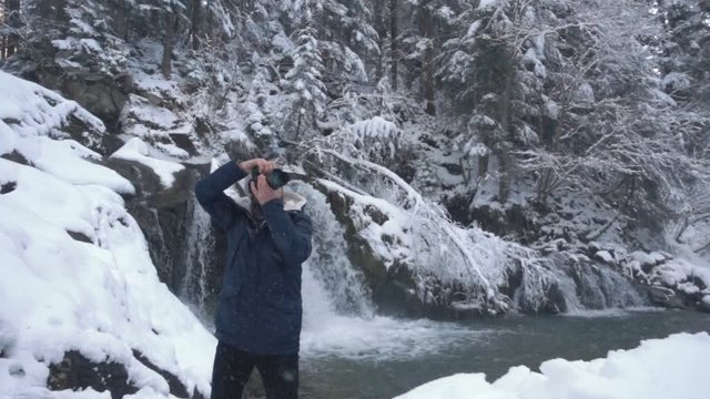 Photographer takes pictures of the frozen waterfall Periknik in the Ukrainian Carpathians