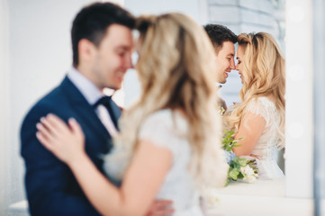 A pair of lovers of happy newlyweds is reflected in a mirror. Bright white studio.