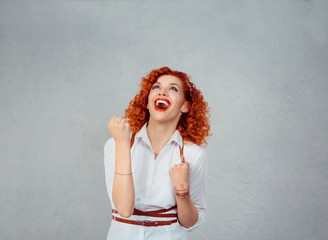 Winner. Happy redhead curly woman exults pumping fists ecstatic celebrates success hands gesture...