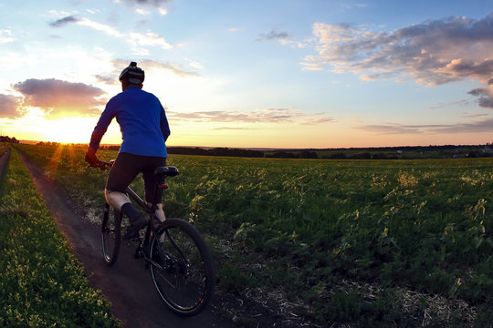 cyclist rides a bicycle on a track at sunset