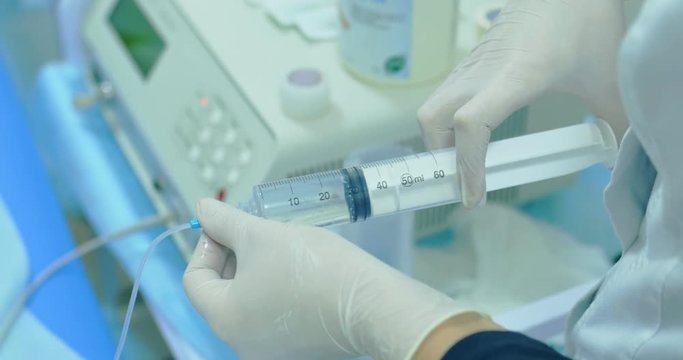 Female medic holding in hands big syringe with hose
