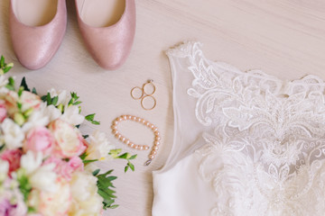 Bridal morning details. Beautiful bouquet of yellow and pink flowers, white wedding dress and leather shoes. Wedding composition, flat lay.
