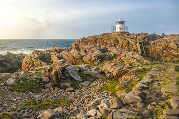 Lighthouse on a rocky shore during a sunset
