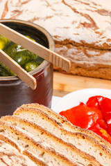 Portion of fresh baked traditional rye or wheat bread and pickled cucumbers in clay pot