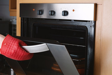 Taking baked tray out of oven with kitchen gloves