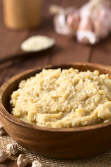 Chickpea spread or hummus with sesame seeds in wooden bowl, photographed with natural light (Selective Focus, Focus one third into the chickpea spread)