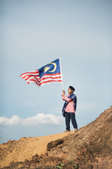 Asian boy dressing traditional holding malaysian flag