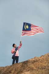 Asian boy dressing traditional holding malaysian flag