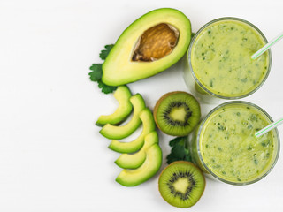 A freshly prepared smoothie of avocado, banana, parsley, lemon and kiwi on a white wooden table. Diet vegetarian food. Raw foods.