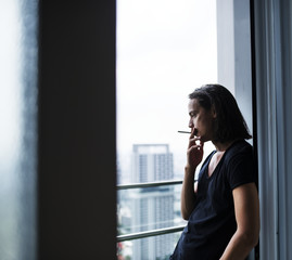 A Western man smoking by the window