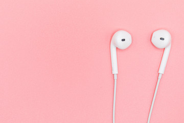 Top view Lovely Closeup of White Earphones on Pink Pastel plastic texture background. Pastel color concept, Minimal concept. Copy space. Music is my life concept. Valentine concept