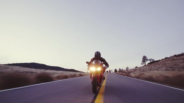 Motorcyclist racing his motorcycle down straight country road going a high speed  at sunset
