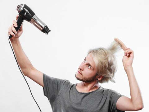 Young man drying hair with hairdryer