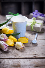 Yellow spring tulips, wrapped  boxes with presents  and blue cup