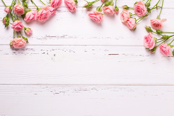 Border from  pink roses flowers  on  white wooden background.