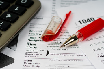 1040 tax form with focus on sign here text and red pen