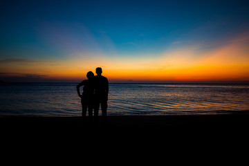 Male silhouette woman standing hugging at the seaside with twilight