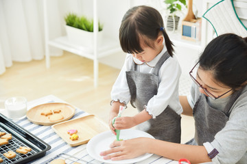 Asian Kid and young mother decorating cookie.