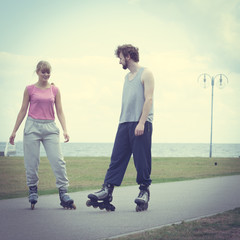 Couple wearing rollerskates looking at each other