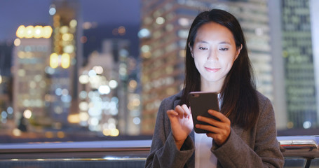 Young Woman use of mobile phone in city at night