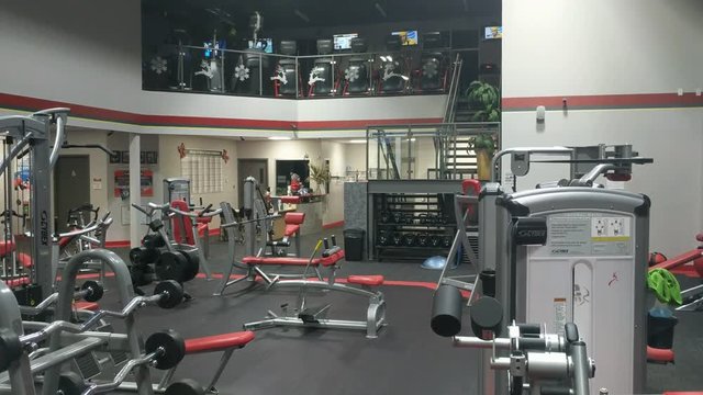 Empty gym facility with exercise equipment, weights, medicine ball racks shot at night.