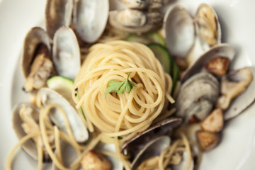 oil pasta with clam on the white dish, wood desk.