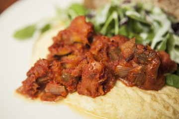 omelet with spicy chicken with bread on the white dish.