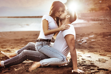 Fashion shot of an attractive couple kissing on a beach