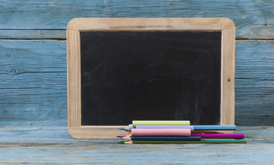 School supplies on blackboard  and empty surface.