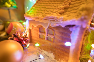 Handmade gingerbread house in luminous garland in the background of christmas decoration