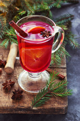 Mulled wine with spices and Christmas tree on wooden background