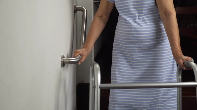Elderly woman holding on handrail for safety walk steps