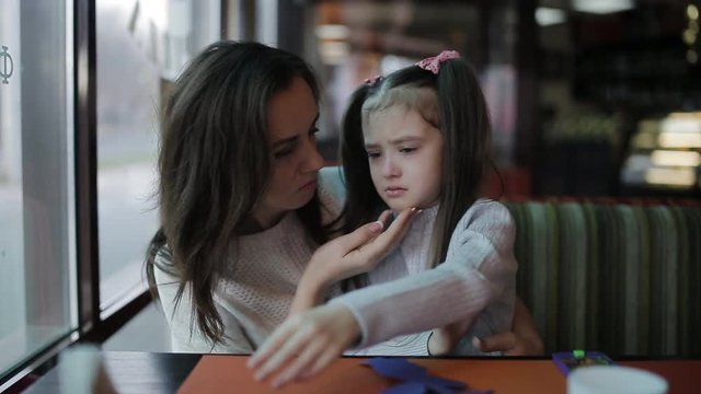 mother soothing and hugging crying baby girl. Beautiful young mother calms crying daughter