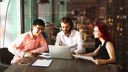 Fototapeta premium Group of young business people are working happily on project in front of big city scene showing options