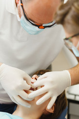Close up process of preparing and installing dental ceramic crown. Male professional dentist helps to treat the teeth of woman patient in clinic light office with modern tools equipment. Open mouth.