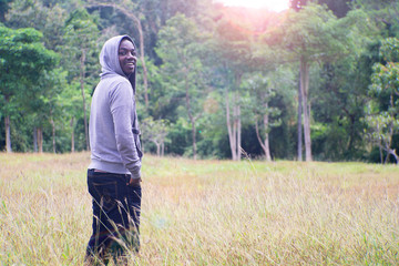 Freedom African Man standing with smile and happy at meadow and green forest with light flare.