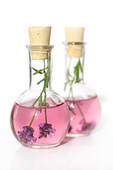 Obraz na płótnie Canvas Lavender flower water. Lavender water in glass bottles and sprigs of lavender on a white background. Infused water with lavender. Organic cosmetics and spa with lavender