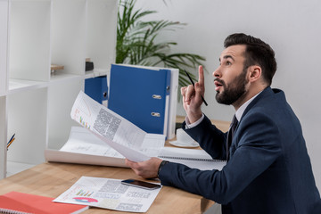 Naklejka premium businessman sitting at table and showing idea gesture