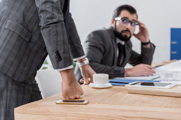 scared businessman sitting at table and looking at team leader