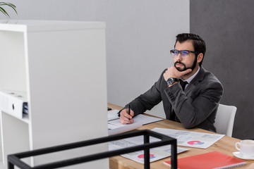 thoughtful businessman sitting at table and looking up