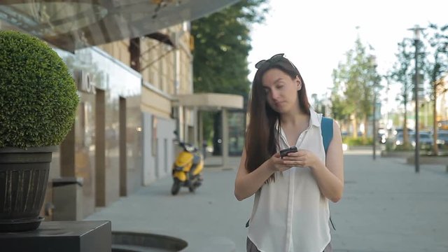 Woman walks around city and searches for sights by phone navigator. Female tourist travels through center and finds architecture through photos on smartphone.