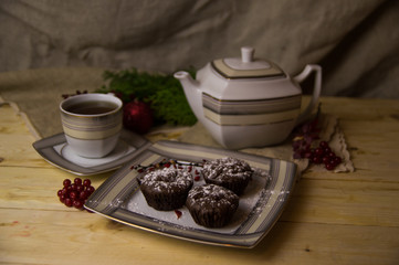 Three chocolate cupcakes with tea on a white tableware of a Christmas table