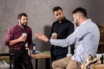 smiling handsome businessmen talking during coffee break at office