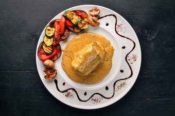 Meat steak with sauce and grilled vegetables. Steak Voronov. On a wooden background. Free space for your text. Top view.
