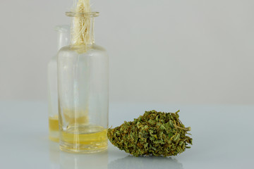 Medical Oil Cannabis - transparent glass apothecary bootle with oil and marijuana flowers on the white background.